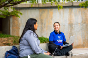 two students sitting and talking on campus