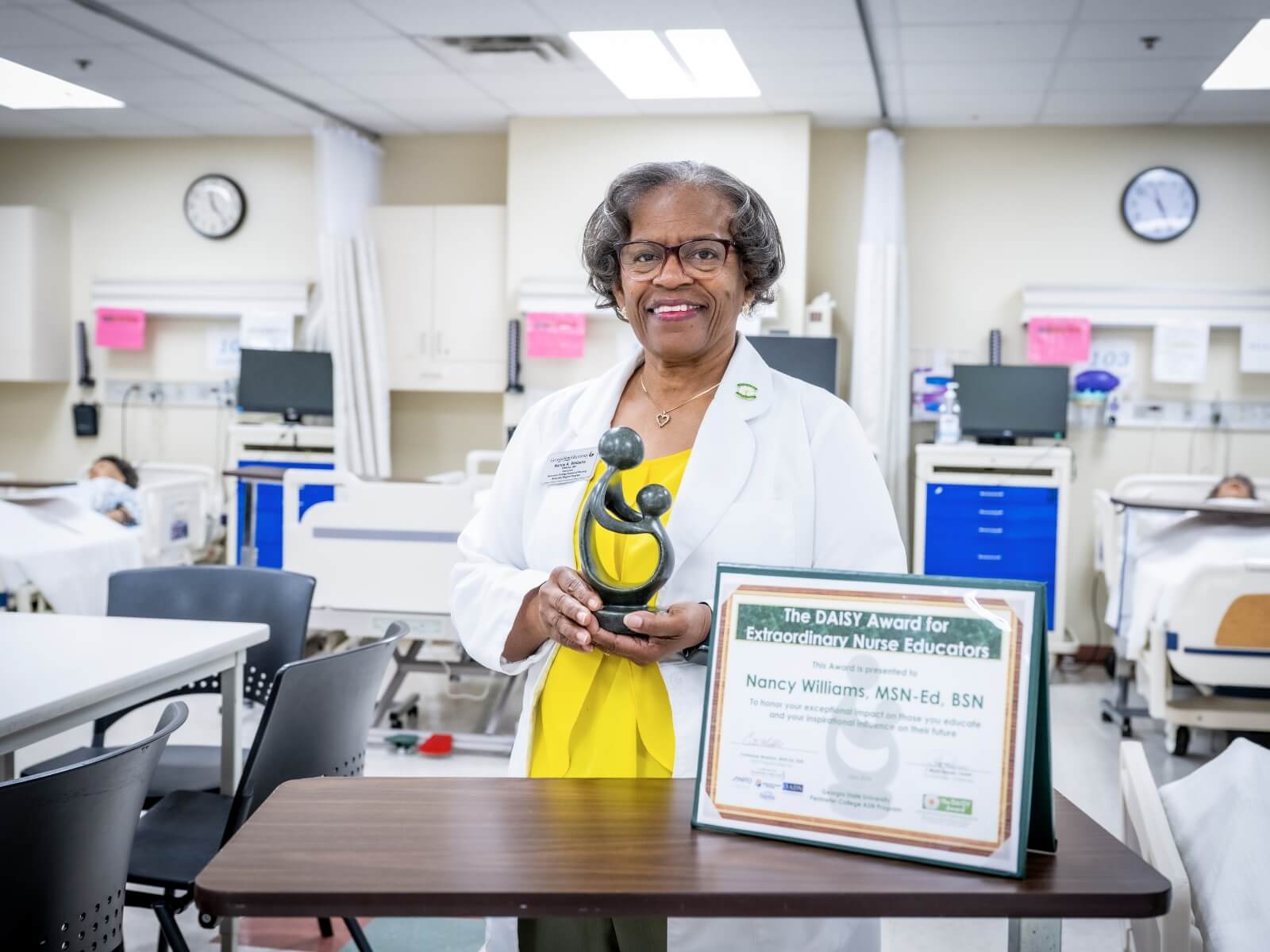 Woman holds award in nurse training clinic