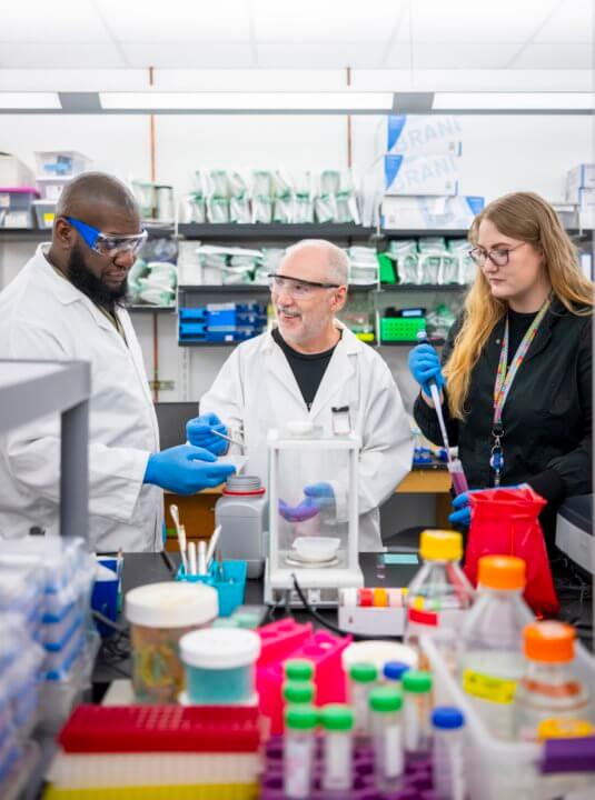 Three scientists work in a lab.