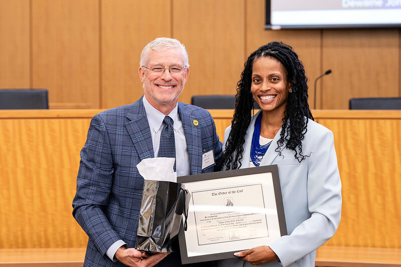 Dean Courtney Anderson presents Jason Poulos (B.S. ‘92, J.D.’97) a certificate commemorating his honorary induction into the Order of the Coif.
