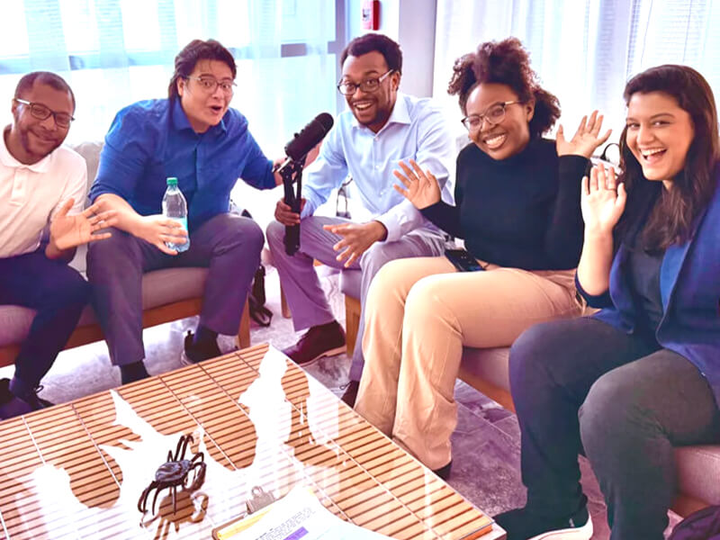 A group seated on couches waving.