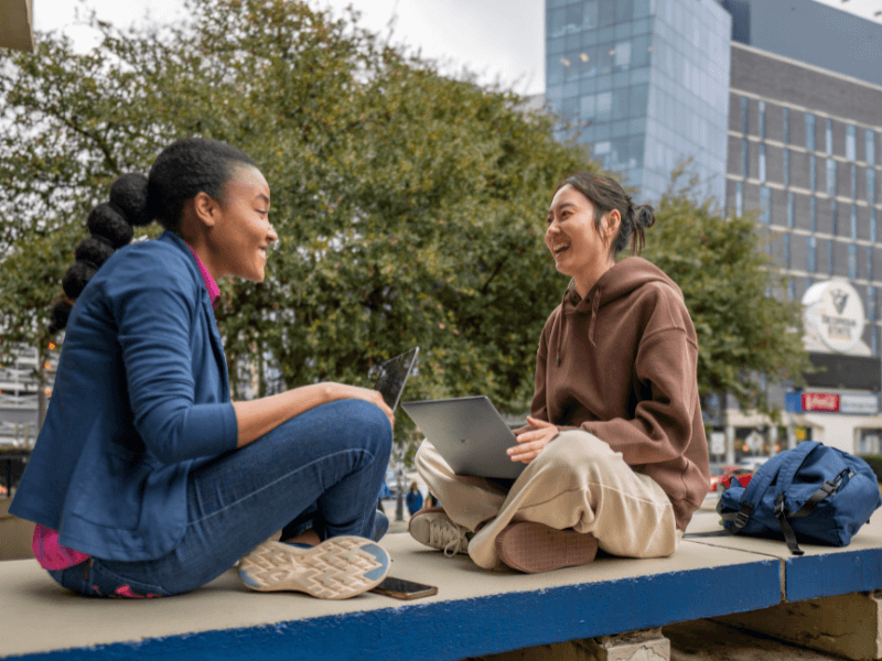 two women sitting down talking outside