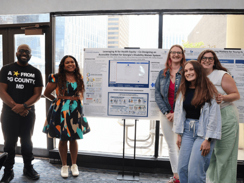 four people psoing in front of a research poster