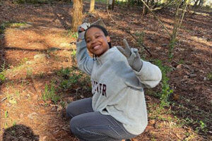 Salem Mututa crouched on the ground holding up a peace sign.