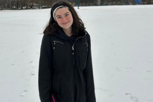 Student standing in a park in the snow.
