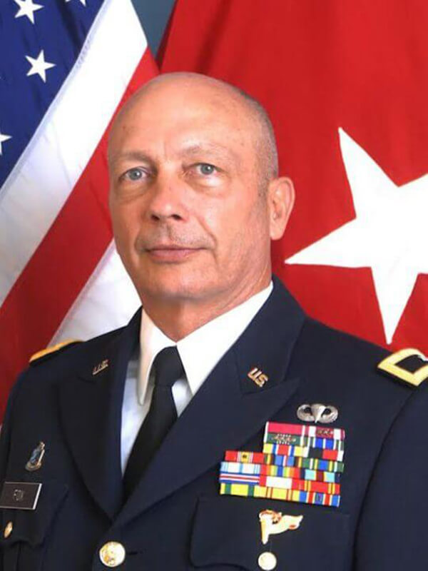 Jack Fox wears his formal military uniform in front of the U.S. flag.
