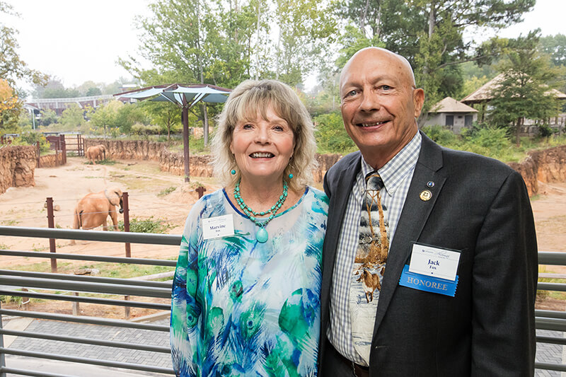 Jack Fox and his wife Marvine Fox stand in front of a fence at the Atlanta Zoo.