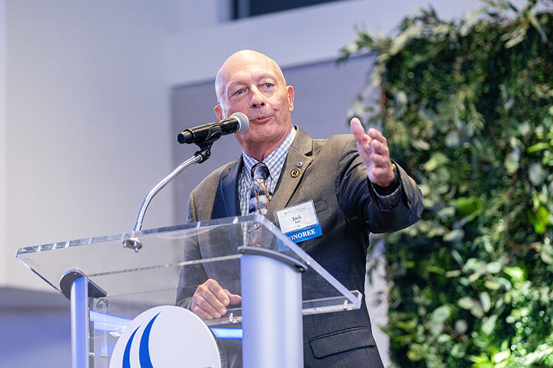 Jack Fox stands and talks at a clear GSU podium wearing a suit and tie.