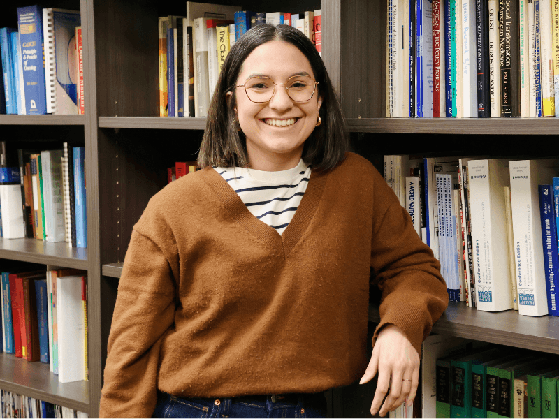 woman smiling next to book shelf