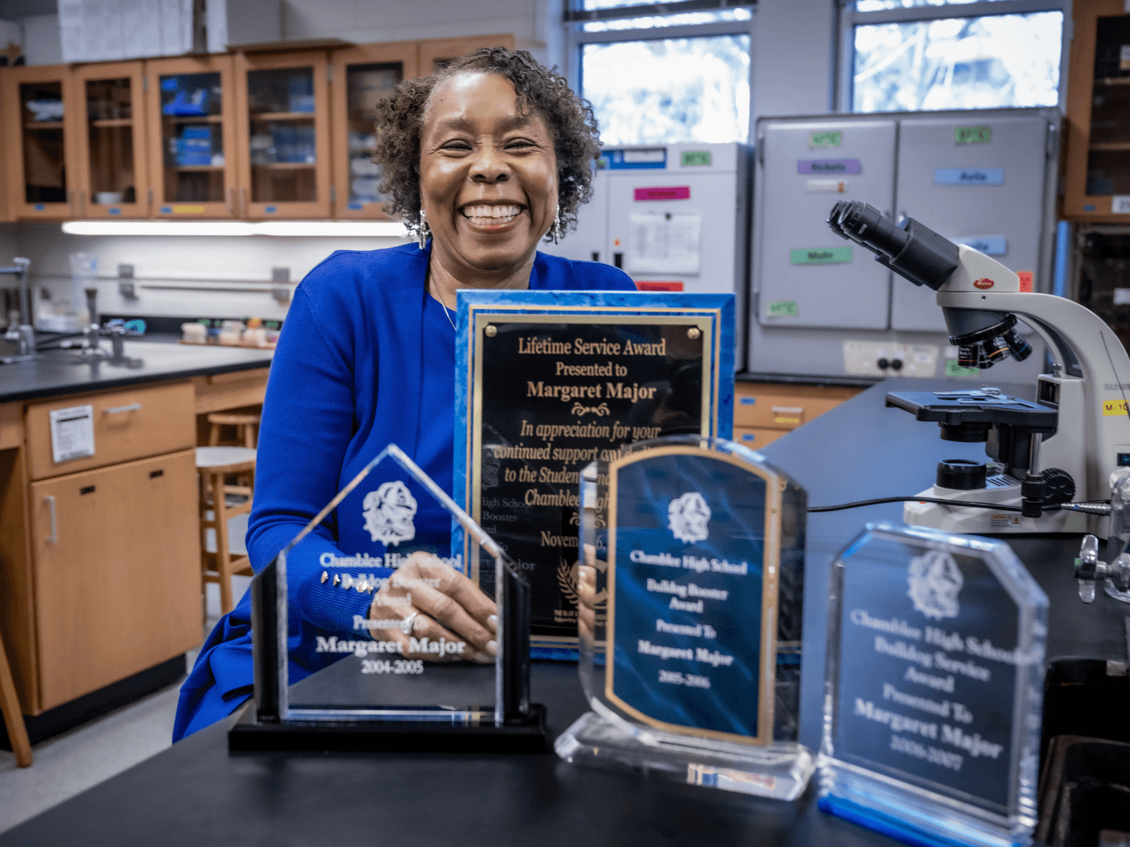 Professor standing in science lab with awards