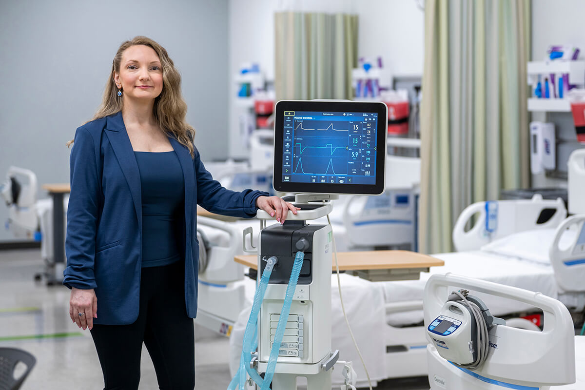 Holly Sangster, Georgia State Alum and Respiratory Therapist Clinical Specialist for Wellstar Health, stands beside mechanical ventilator.