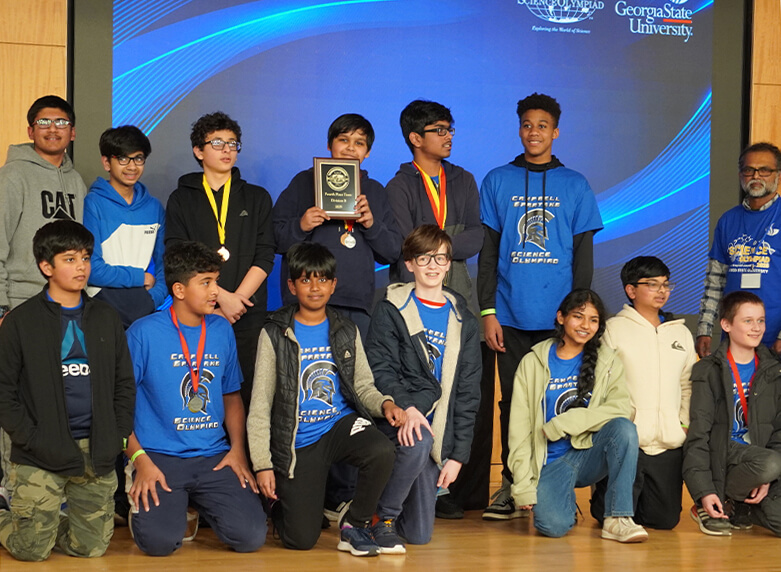 Science Olympiad winners on stage with medals.