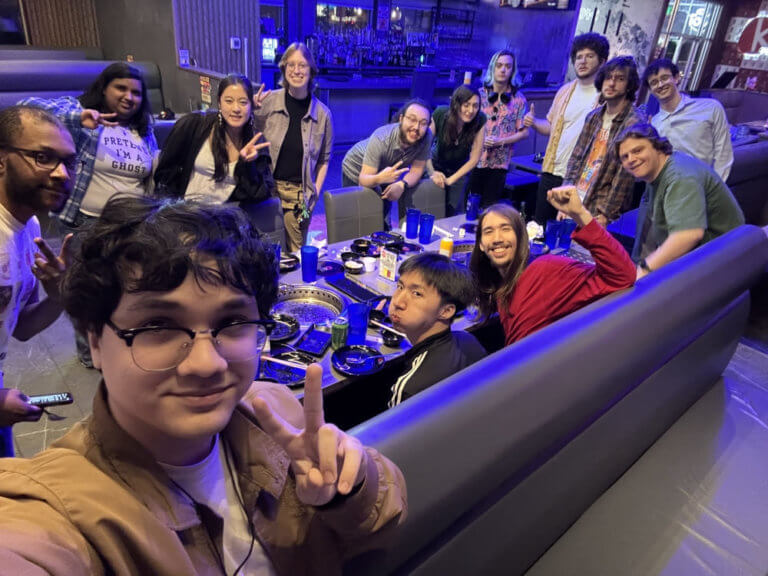 Students around a table take a selfie.