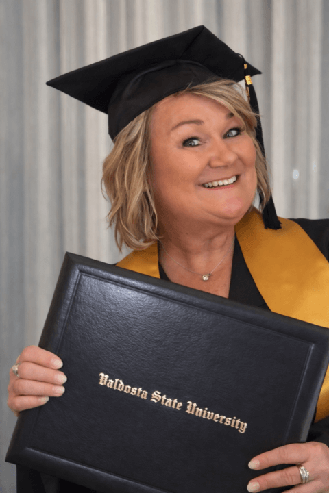 Woman in cap and gown with diploma