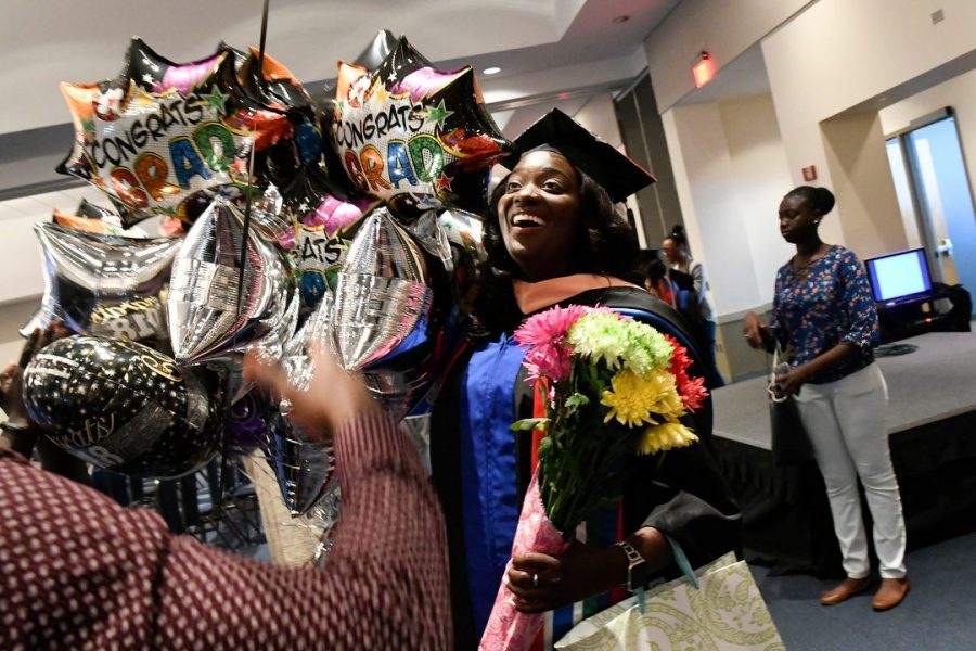 A School of Public Health graduate is greeted with several, large balloons and colorful flowers