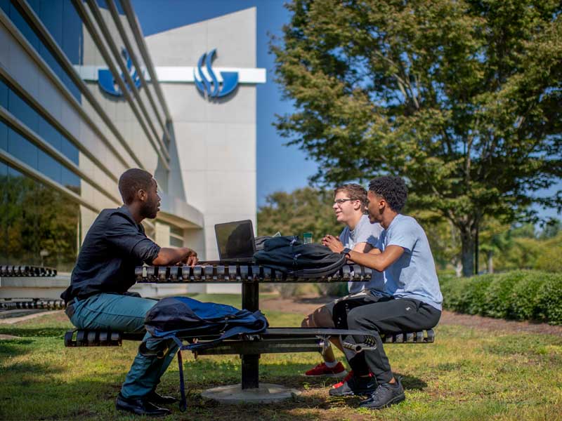 three male students talking on the outside table in Perimeter College Alpharetta campus