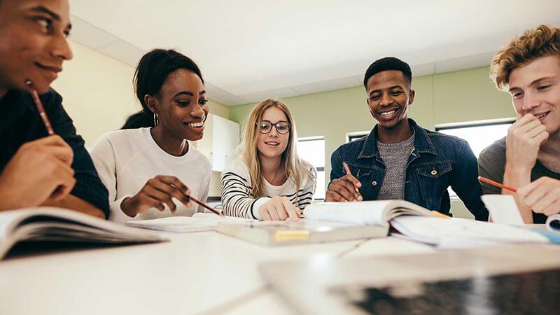 A group of students laughing while studying at a table.