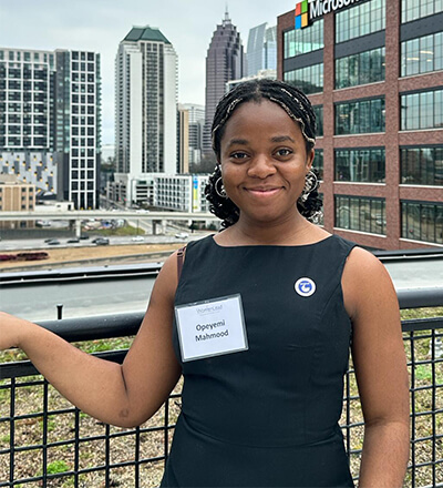 Student on a balcony with the Atlanta skyline in the background.