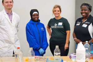 Perimeter College professors and students pose in front of table with chemistry items.