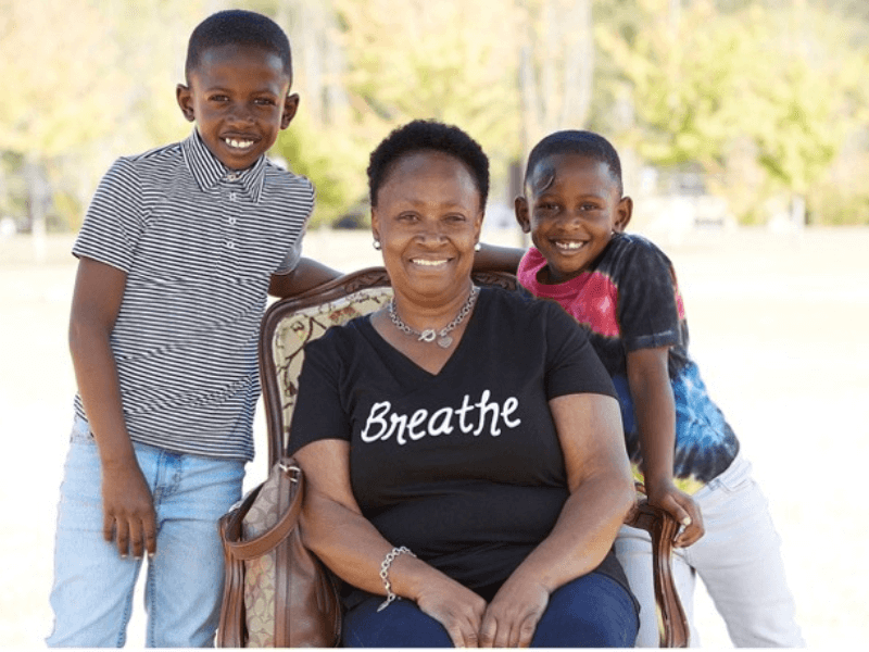 Woman seated with two young boys standing beside her.