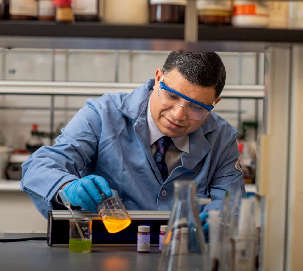 A researcher in a lab with glass beakers.
