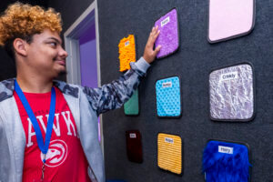 A student touching different patches of textures on the wall.