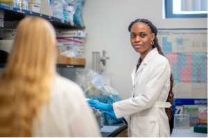 Iyanu in the lab with blue gloves looking to the right