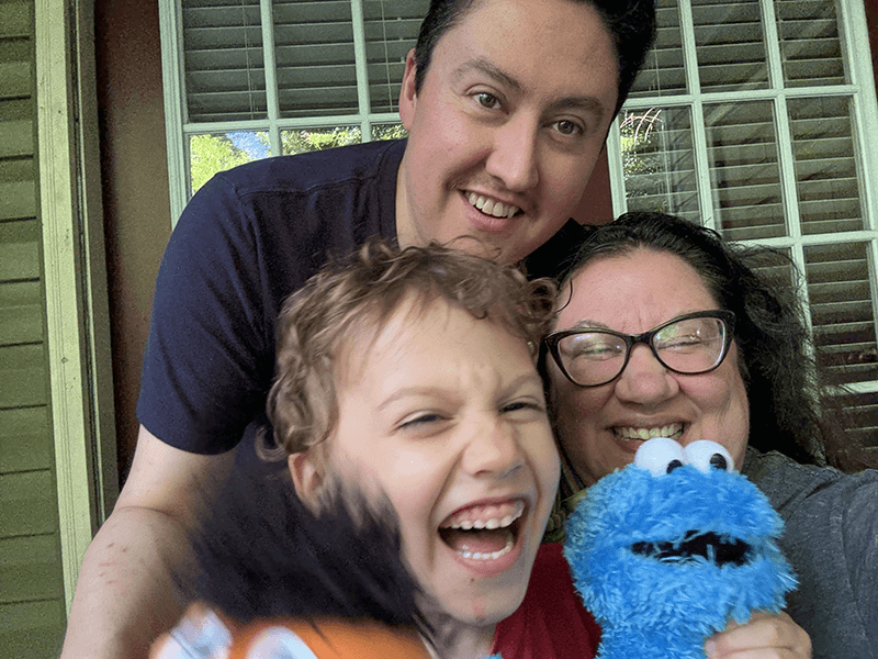Marc Reyes taking a photo with his son holding two toys, and embracing his wfe 