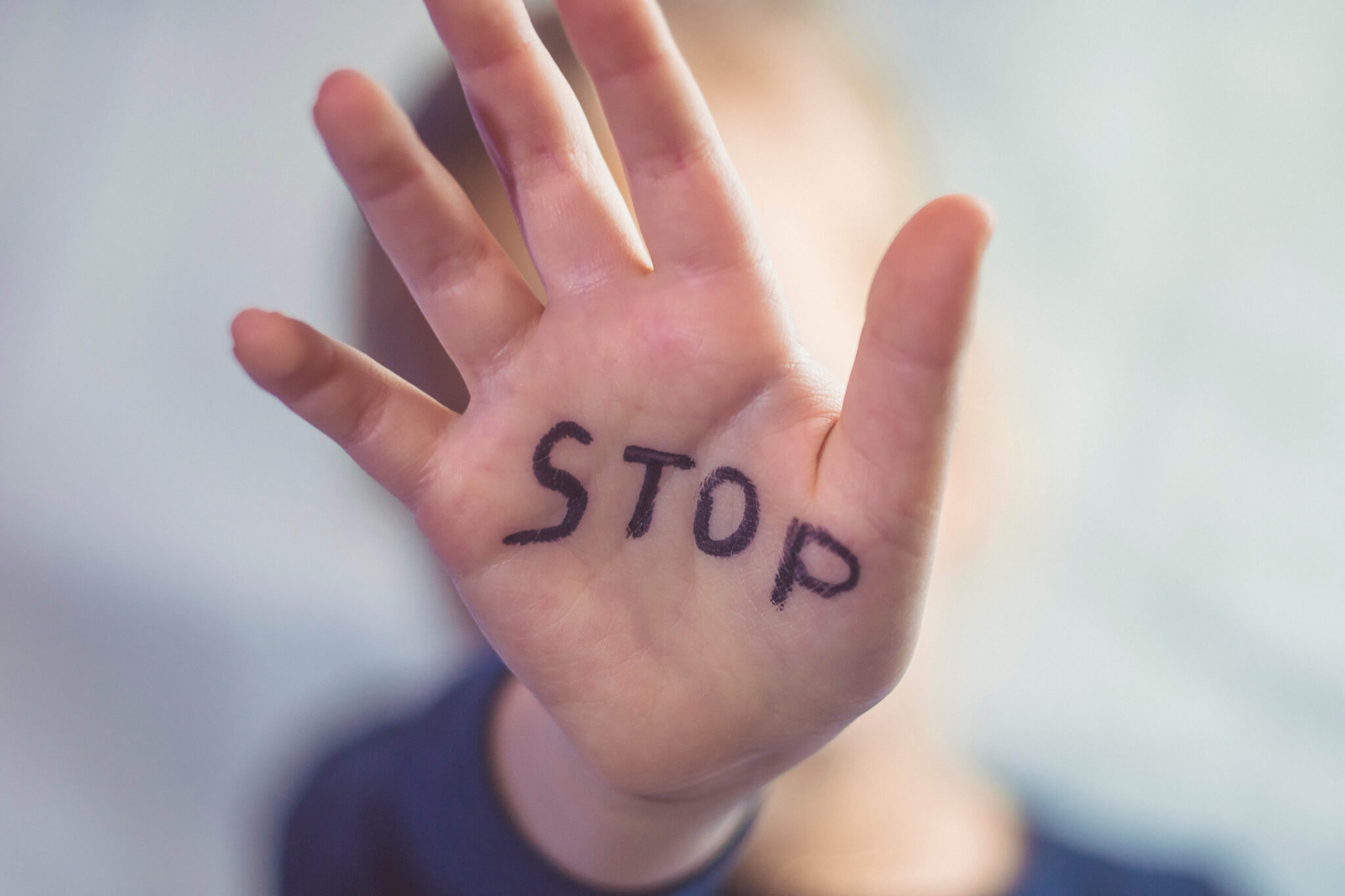 A little girl shows her hand with the word STOP written on it.