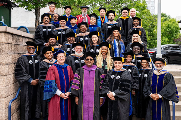 Doctor of Business Administration graduates stand on the steps with program faculty and Dean Phillips.