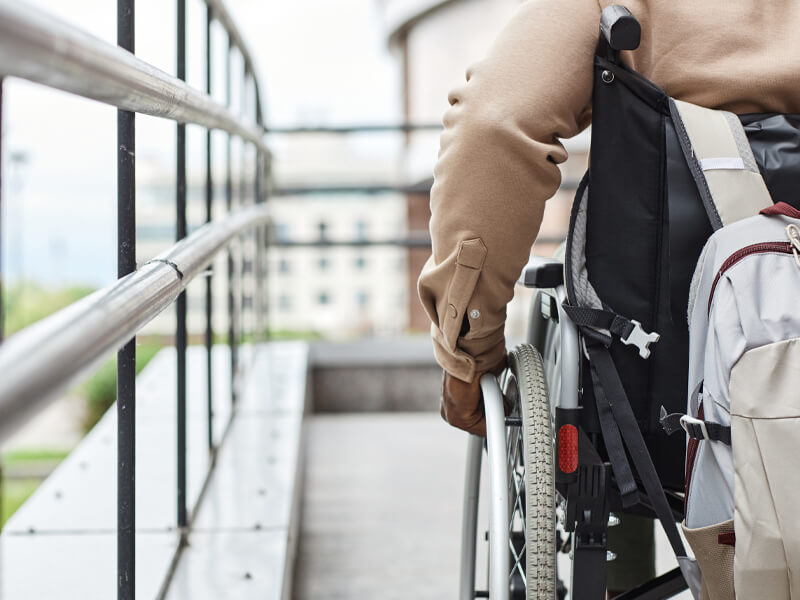 Wheelchair user on an accessible ramp, representing housing challenges facing disabled veterans