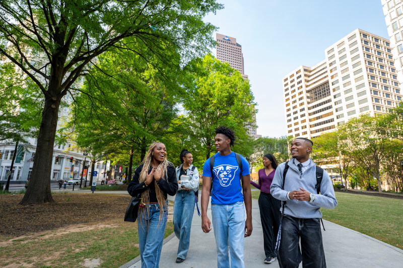 Students walking through the park in the GSU campus in front of the Andrew Young School building