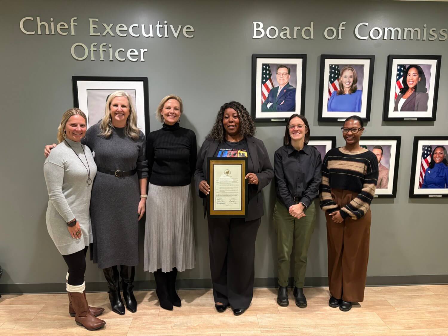 Group of women in a row with one holding a framed proclamation.