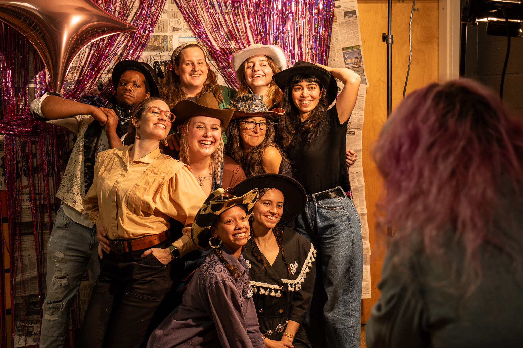 Young people pose for a photo against a backdrop of purple curtains.
