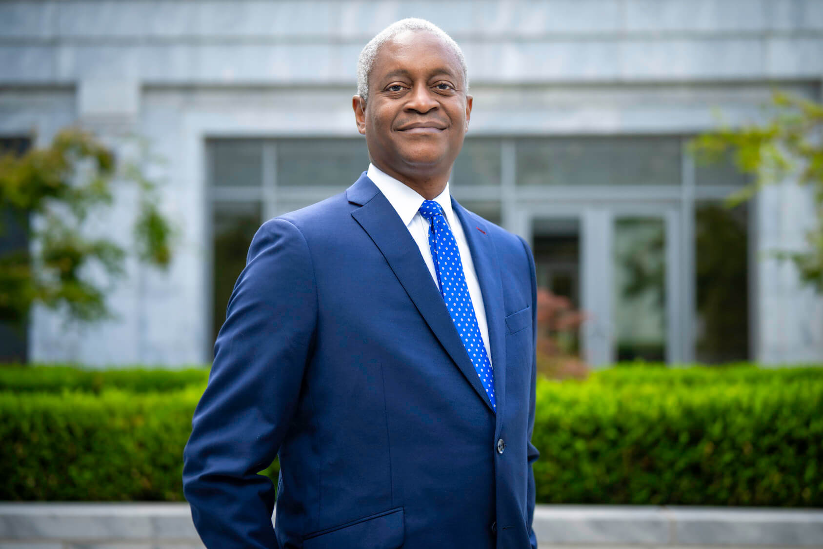 Raphael Bostic in blue blazer and light blue tie standing in front of the Atlanta Federal Reserve